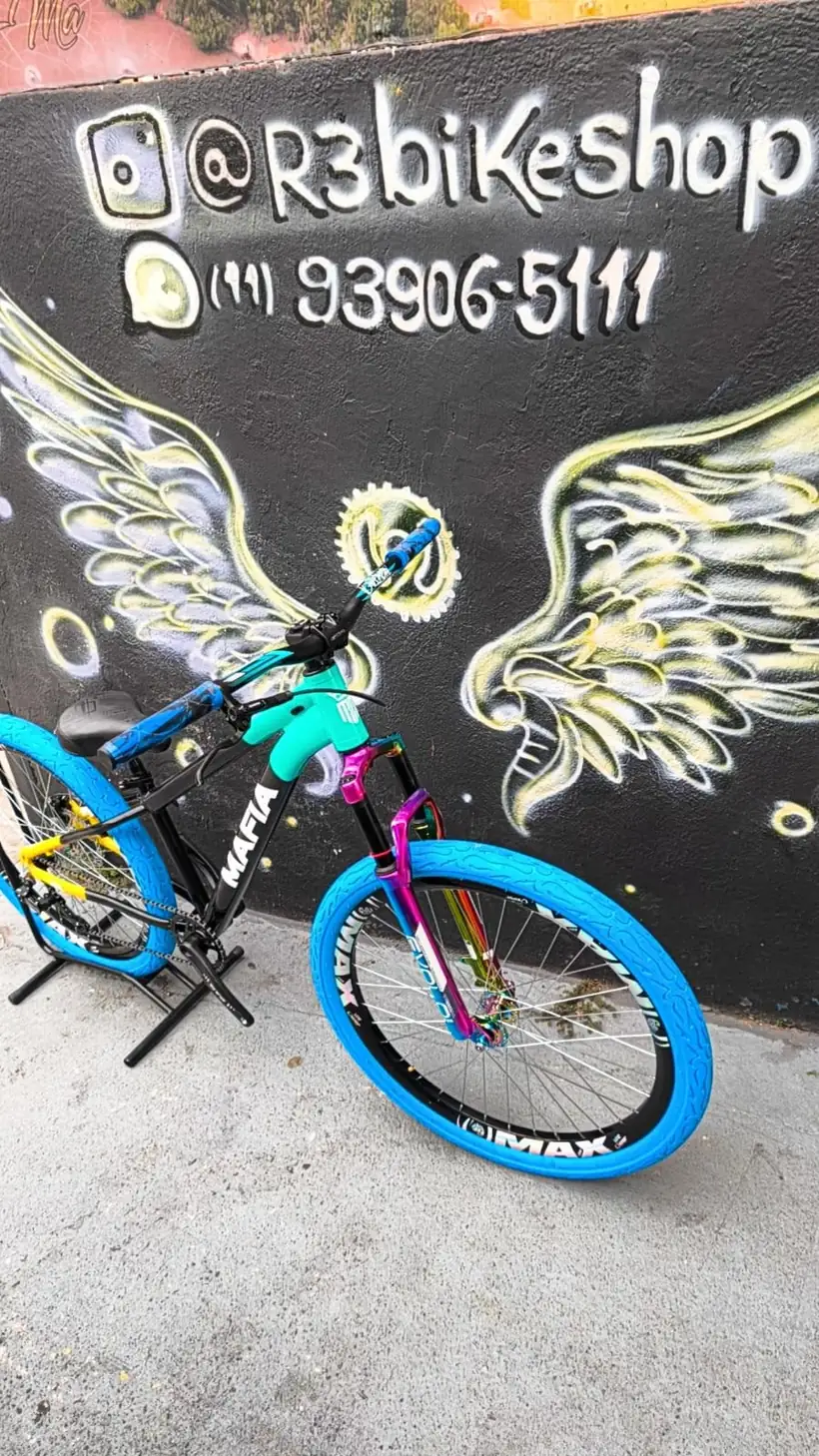 Bicicleta azul clara diante do mural de asas da R3 Bike Shop
