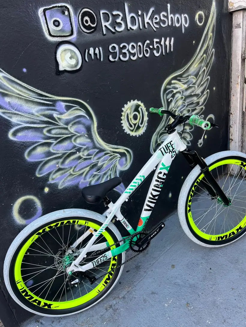 Bicicleta branca e verde limão diante do mural de asas da R3 Bike Shop