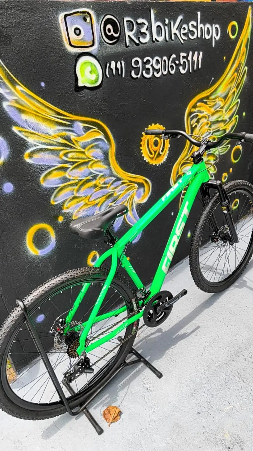 Bicicleta verde diante do mural de asas da R3 Bike Shop